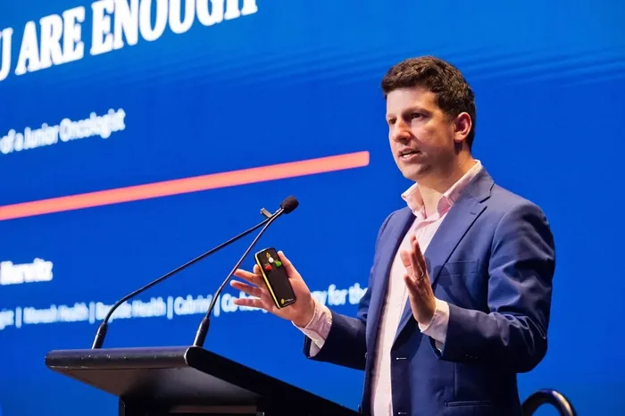 Dr Joshua Hurwitz presenting at a lectern to oncology trainees at the Medical Oncology Group of Australia conference, 2026