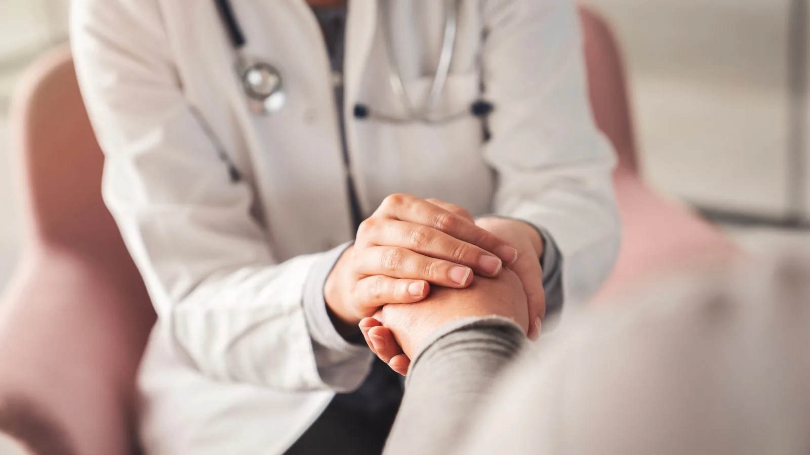 A doctor reassuringly holding a patient's hand